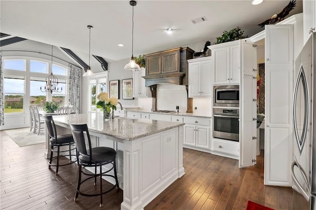 6840 Belmont Dr, Shawnee, KS 66226 - kitchen with appliances with stainless steel finishes, dark wood finished floors, white cabinetry, a breakfast bar area, and lofted ceiling