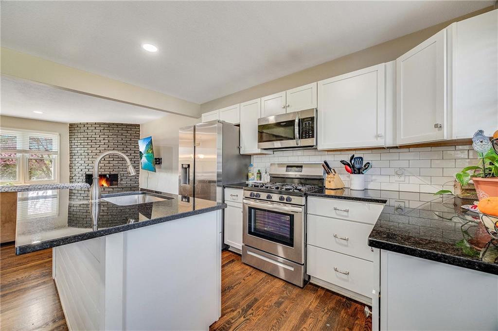 2109 S 9th St, Kansas City, KS 66103 - kitchen with white cabinets, a sink, dark stone counters, decorative backsplash, and appliances with stainless steel finishes