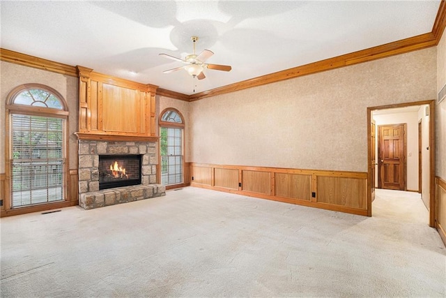 unfurnished living room featuring plenty of natural light, ornamental molding, a ceiling fan, and light carpet
