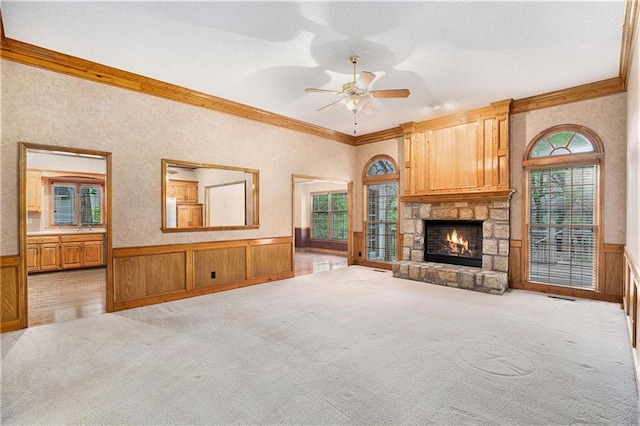 unfurnished living room featuring a wealth of natural light, crown molding, and wainscoting