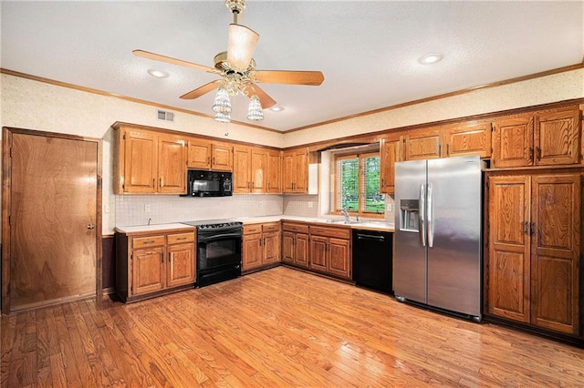 kitchen with crown molding, black appliances, visible vents, and brown cabinetry