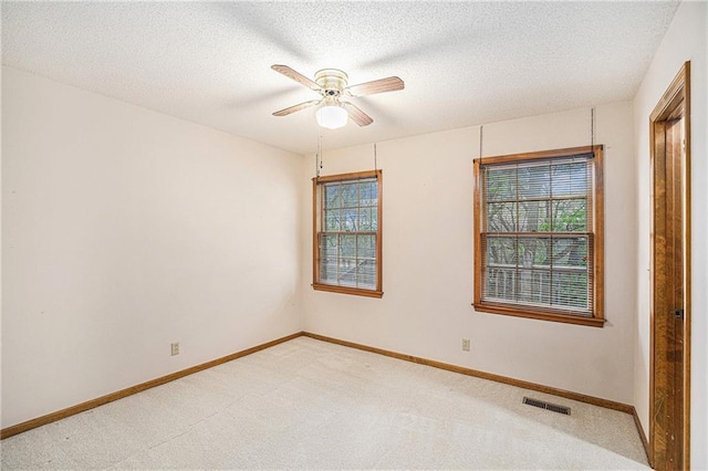 unfurnished room featuring light colored carpet, visible vents, ceiling fan, and baseboards