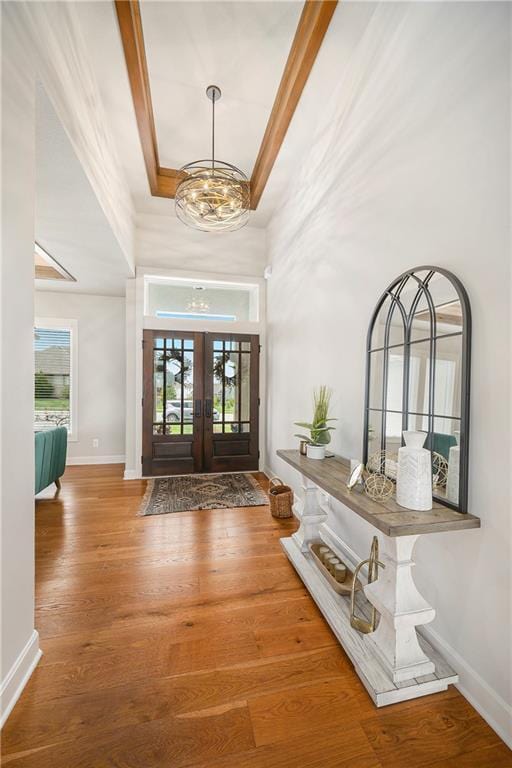 foyer with wood finished floors, a chandelier, a high ceiling, french doors, and baseboards