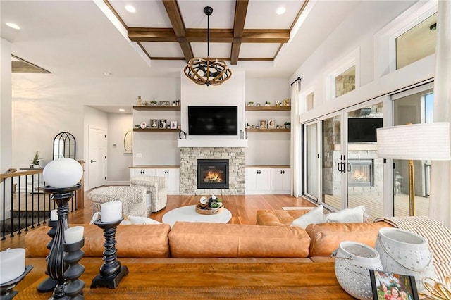 living room featuring coffered ceiling, beam ceiling, wood finished floors, and a stone fireplace