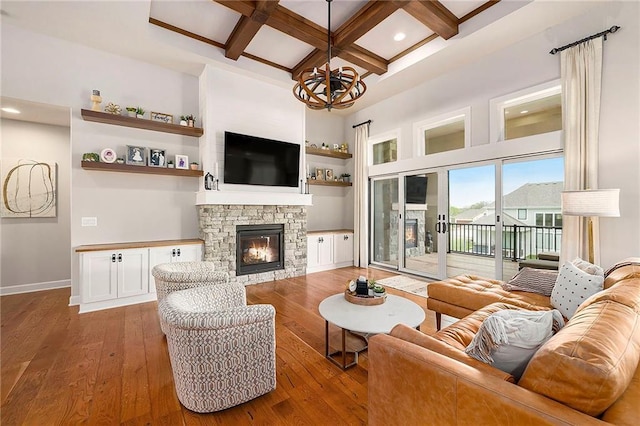 living area featuring a stone fireplace, coffered ceiling, hardwood / wood-style floors, and beamed ceiling