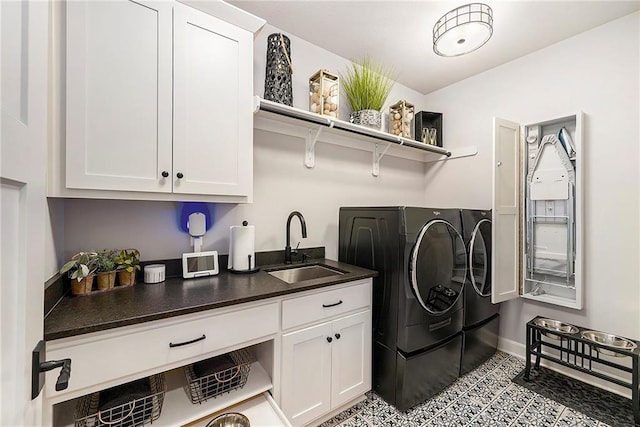 clothes washing area with cabinet space, washing machine and clothes dryer, baseboards, and a sink