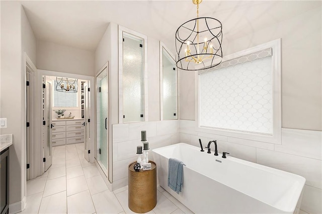 bathroom featuring a stall shower, vanity, a freestanding bath, a notable chandelier, and tile patterned flooring