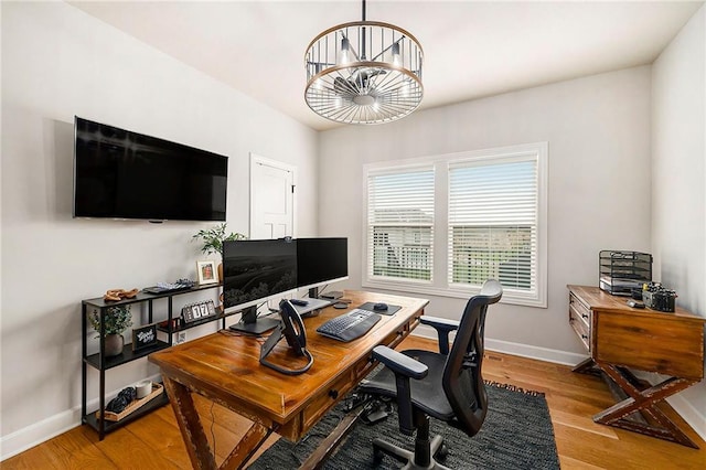 office space featuring baseboards, wood finished floors, and a chandelier
