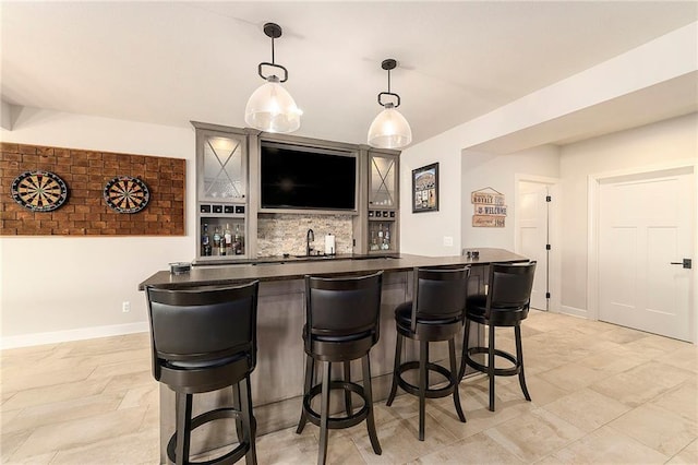 bar with a sink, wet bar, baseboards, decorative backsplash, and hanging light fixtures