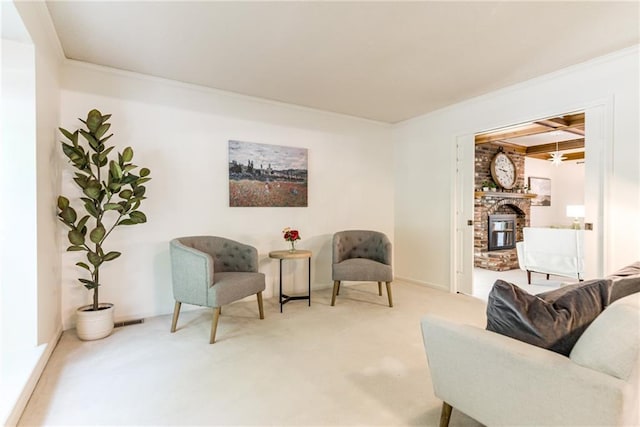 living area with carpet floors, ornamental molding, a fireplace, and beamed ceiling