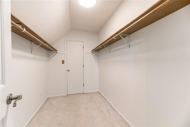 walk in closet with light carpet and lofted ceiling