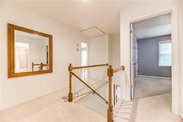 hall featuring an upstairs landing, carpet floors, and baseboards