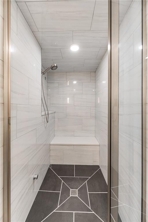 full bath with tiled shower and tile patterned flooring