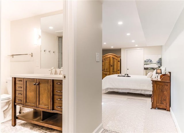 bedroom featuring baseboards, recessed lighting, ensuite bathroom, and a sink