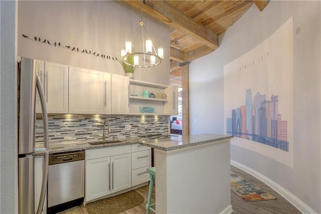 kitchen with tasteful backsplash, a sink, beam ceiling, wood finished floors, and stainless steel appliances