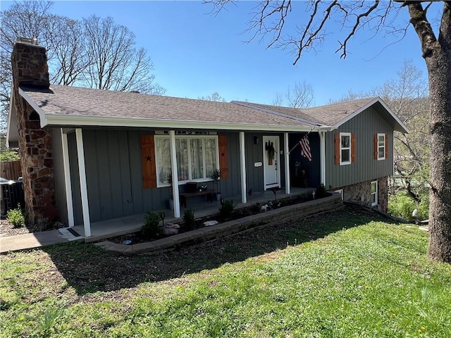 single story home with board and batten siding, a porch, roof with shingles, a front yard, and a chimney