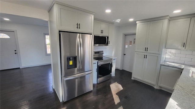 kitchen with appliances with stainless steel finishes, dark wood-type flooring, decorative backsplash, light stone countertops, and recessed lighting