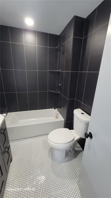 bathroom with tile walls, toilet, tile patterned floors, washtub / shower combination, and vanity