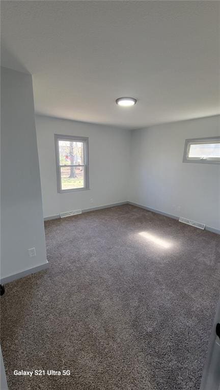 empty room featuring plenty of natural light, carpet floors, and baseboards