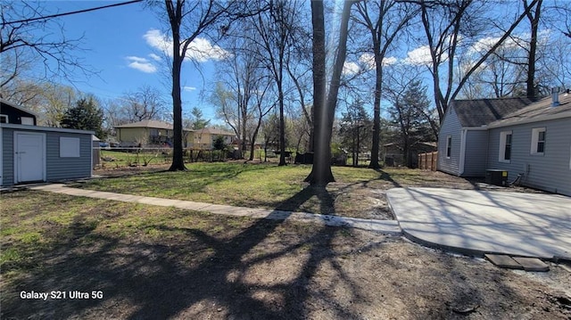 view of yard with fence, an outbuilding, a storage unit, and central air condition unit