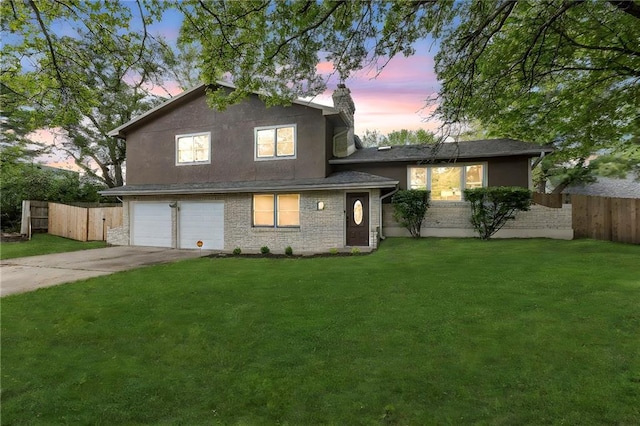 split level home with fence, an attached garage, and a lawn