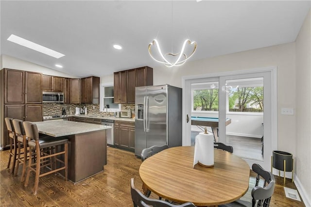 kitchen featuring a kitchen island, appliances with stainless steel finishes, tasteful backsplash, light countertops, and a sink