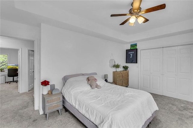 bedroom featuring a tray ceiling, carpet floors, ceiling fan, and a closet