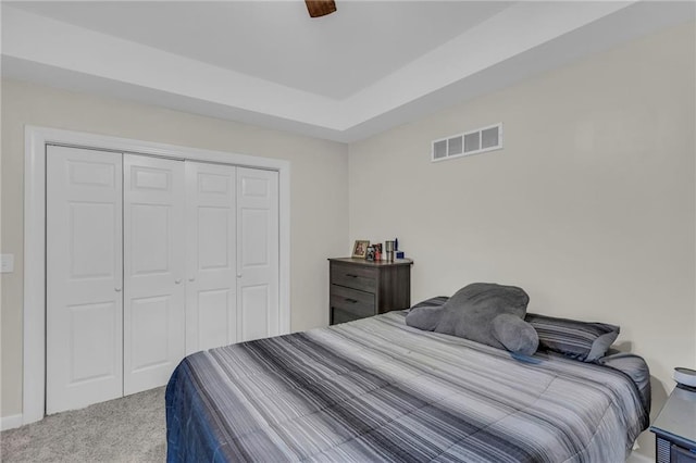 carpeted bedroom featuring a ceiling fan, a closet, and visible vents