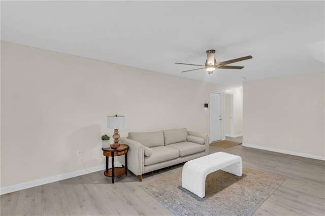 living room featuring baseboards, ceiling fan, and wood finished floors