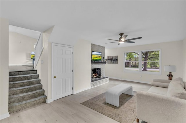 living room with stairs, wood finished floors, a fireplace, baseboards, and ceiling fan
