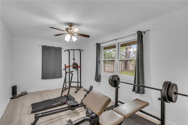 exercise area featuring baseboards, a ceiling fan, and wood finished floors
