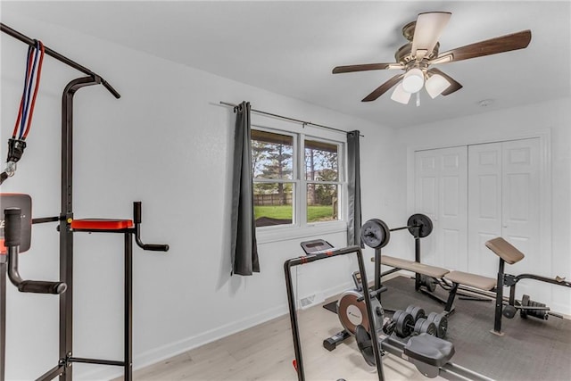 workout room with baseboards, ceiling fan, and wood finished floors