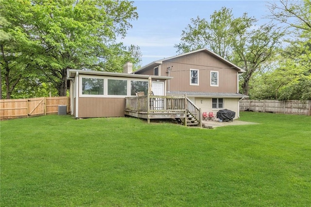 rear view of property featuring a deck, a fenced backyard, a chimney, cooling unit, and a lawn