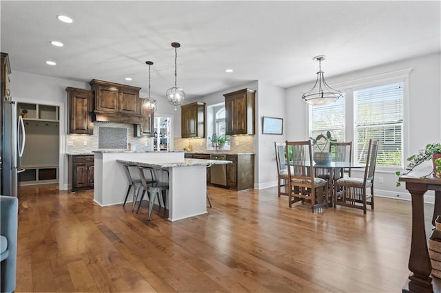kitchen featuring stainless steel appliances, a kitchen island, backsplash, dark wood finished floors, and recessed lighting