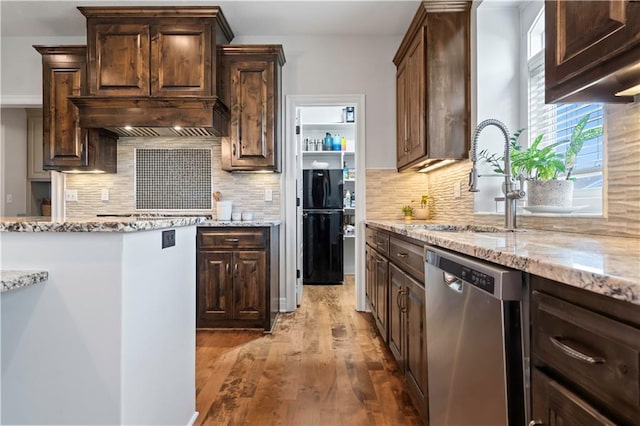 kitchen with appliances with stainless steel finishes, light wood-style flooring, light stone countertops, and dark brown cabinetry