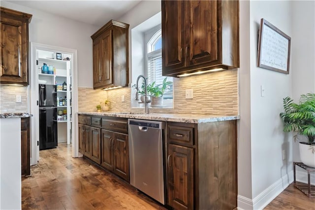 kitchen with dishwasher, a sink, wood finished floors, dark brown cabinets, and tasteful backsplash