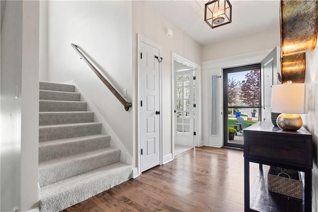 foyer entrance with stairway, wood finished floors, and baseboards