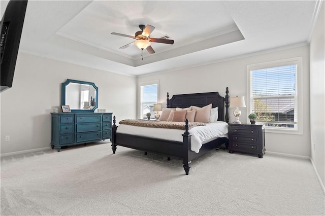 bedroom featuring a raised ceiling, light colored carpet, ornamental molding, baseboards, and ceiling fan