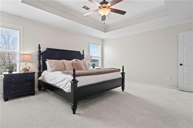 bedroom featuring a raised ceiling, ornamental molding, light carpet, baseboards, and ceiling fan