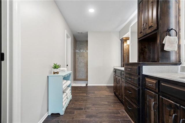 bathroom with double vanity, wood finished floors, baseboards, and recessed lighting