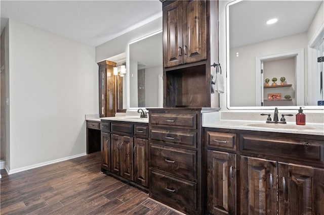 bathroom featuring wood finished floors, double vanity, baseboards, and recessed lighting