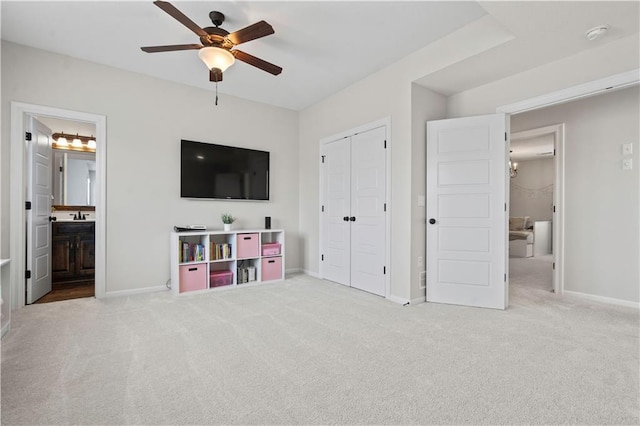 unfurnished bedroom featuring carpet flooring, baseboards, a closet, ensuite bath, and a ceiling fan