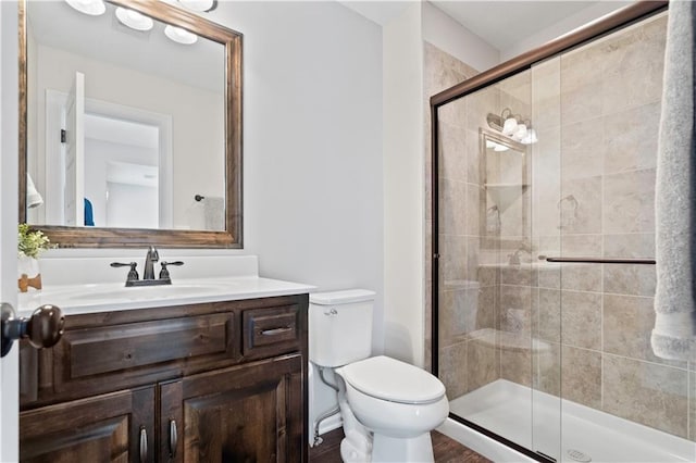 bathroom with a stall shower, toilet, and vanity