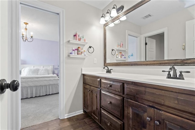 ensuite bathroom with wood finished floors, double vanity, and a chandelier
