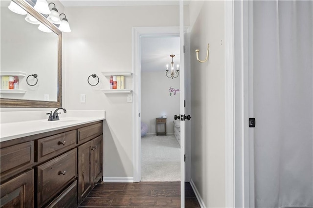 bathroom featuring wood finished floors, a chandelier, vanity, and baseboards