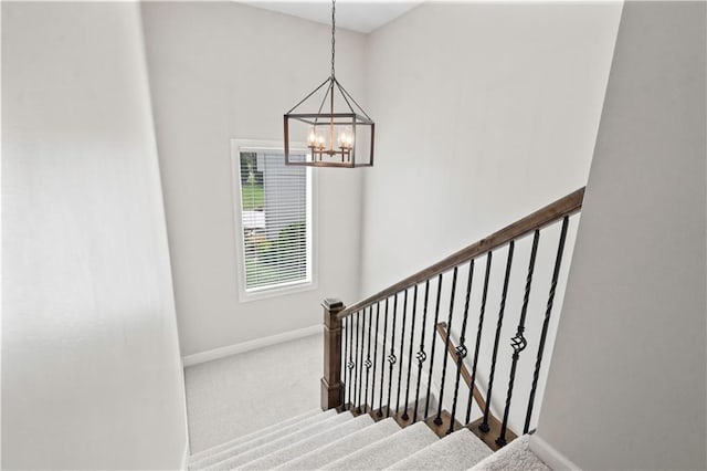staircase with baseboards, a chandelier, and carpet flooring