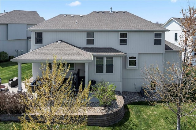 back of house featuring a shingled roof and a lawn