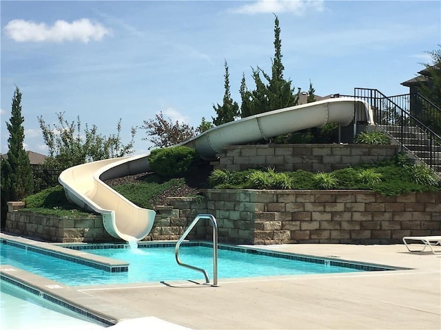 view of pool featuring a water slide, stairs, and a patio