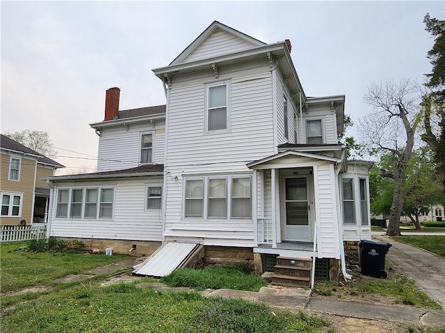 back of property with entry steps and a chimney
