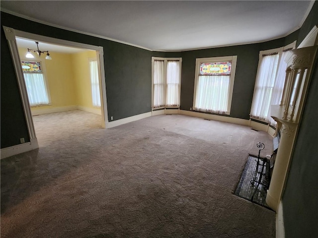 spare room featuring a chandelier, a healthy amount of sunlight, baseboards, and carpet